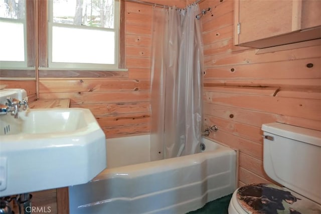 full bathroom with shower / tub combo, wooden walls, toilet, and a sink