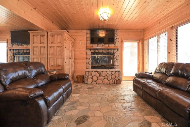 living area featuring stone flooring, a stone fireplace, and wooden ceiling