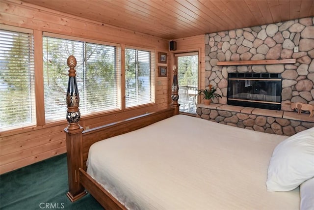 bedroom with access to exterior, wooden ceiling, wooden walls, a fireplace, and carpet
