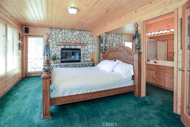 bedroom featuring wooden ceiling, a stone fireplace, wood walls, and carpet floors