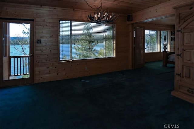 unfurnished dining area with a notable chandelier, wood walls, carpet floors, and wood ceiling