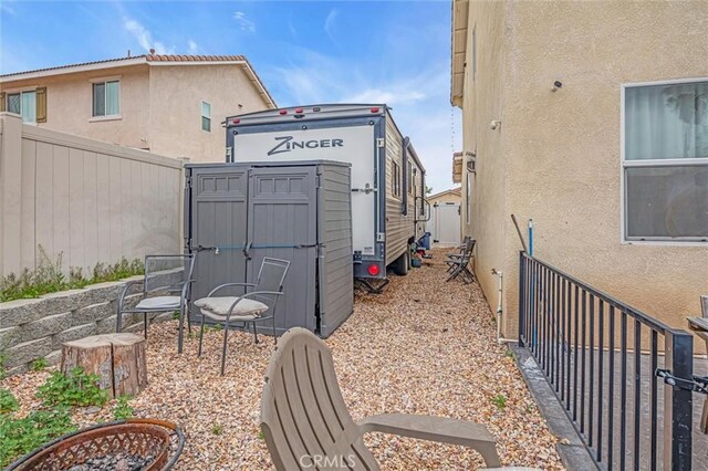 1781 Terrace Ave, Colton, CA 92324 - view of side of home featuring stucco siding, fence, a storage unit, and an outbuilding