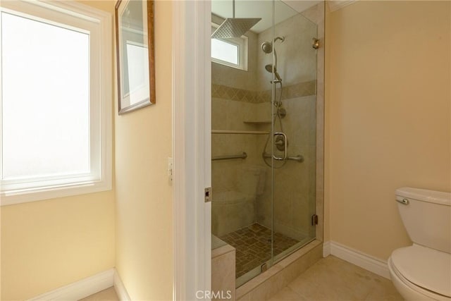 bathroom featuring tile patterned floors, toilet, a stall shower, and baseboards