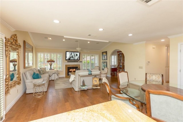dining space featuring crown molding, a fireplace, wood finished floors, and baseboards