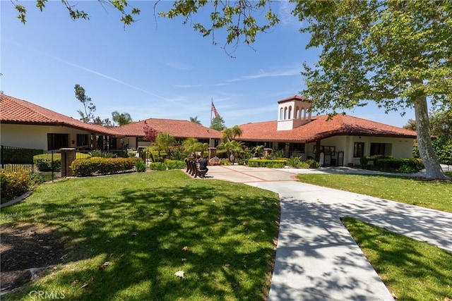mediterranean / spanish-style home featuring a front yard, stucco siding, and fence