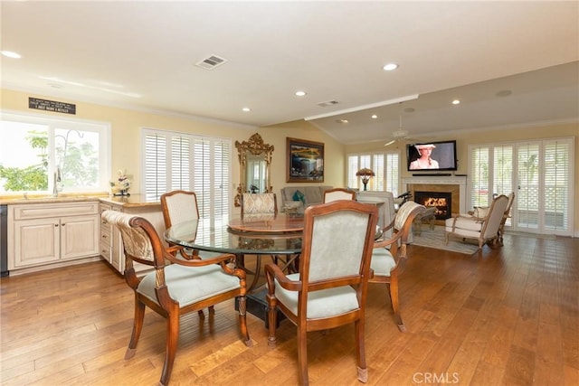 dining space with a fireplace, visible vents, and light wood-type flooring