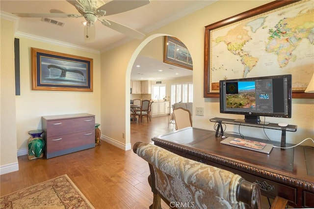 office space with wood finished floors, arched walkways, visible vents, a ceiling fan, and crown molding