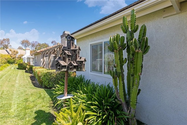 view of property exterior with stucco siding and a lawn