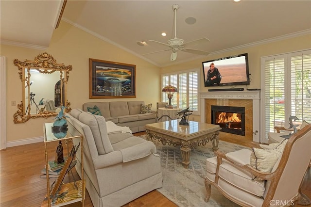 living room featuring crown molding, baseboards, a tile fireplace, wood finished floors, and a ceiling fan