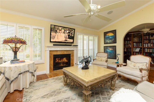 living area featuring wood finished floors, crown molding, ceiling fan, a high end fireplace, and lofted ceiling