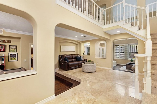 living area with arched walkways, stairway, baseboards, marble finish floor, and ornamental molding