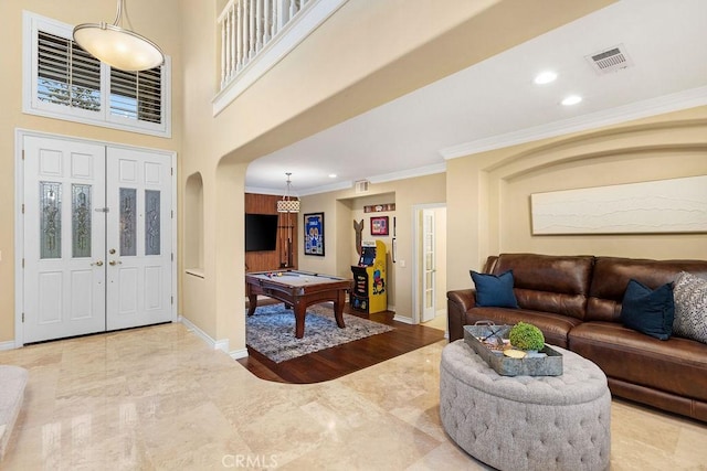 foyer with billiards, visible vents, arched walkways, baseboards, and ornamental molding