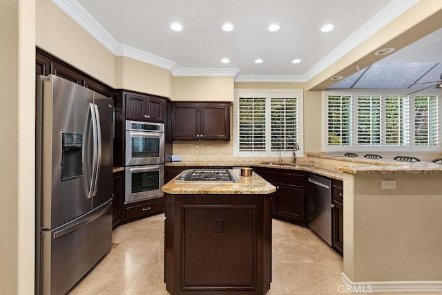 kitchen featuring a kitchen island, appliances with stainless steel finishes, dark brown cabinets, a sink, and ornamental molding