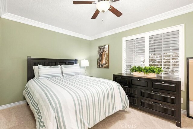 bedroom featuring carpet flooring, a ceiling fan, crown molding, and baseboards
