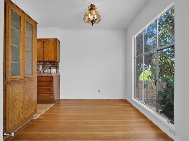 unfurnished dining area with light wood finished floors and a notable chandelier