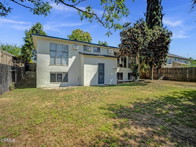 rear view of property featuring a yard, a fenced backyard, and stucco siding