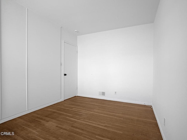 spare room with baseboards, wood finished floors, and visible vents