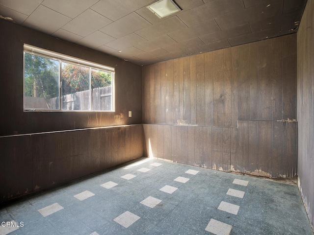 unfurnished room with wooden walls and tile patterned floors