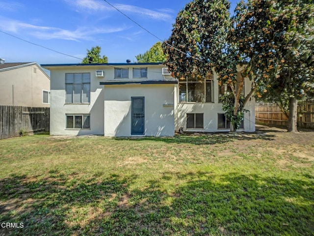 rear view of house featuring a lawn, a fenced backyard, and stucco siding