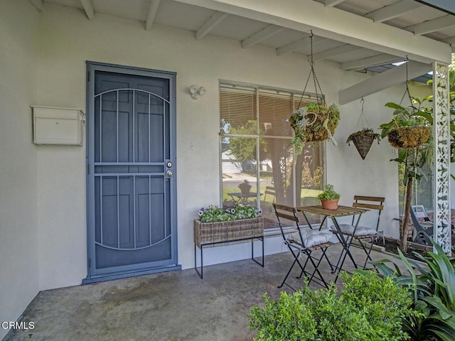 entrance to property featuring stucco siding and covered porch