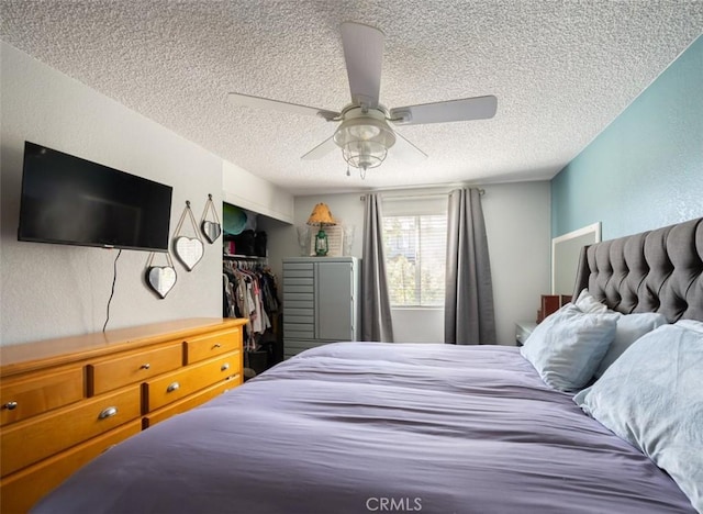 bedroom with a textured ceiling, ceiling fan, and a textured wall