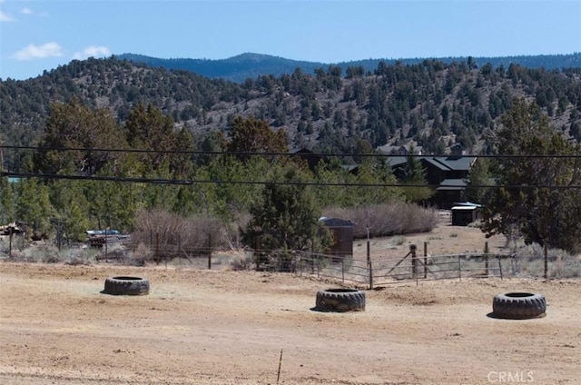view of yard with fence, a rural view, a mountain view, and a view of trees