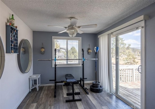 workout area featuring a textured ceiling, a ceiling fan, wood finished floors, and baseboards