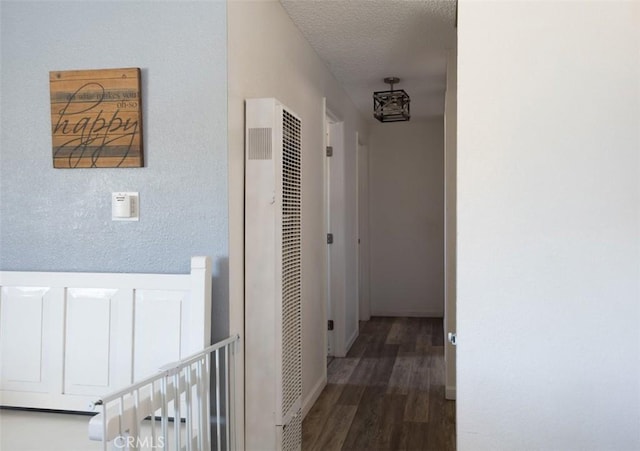 hall featuring baseboards, wood finished floors, and a heating unit