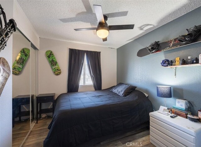 bedroom with a textured ceiling, wood finished floors, ceiling fan, and a closet