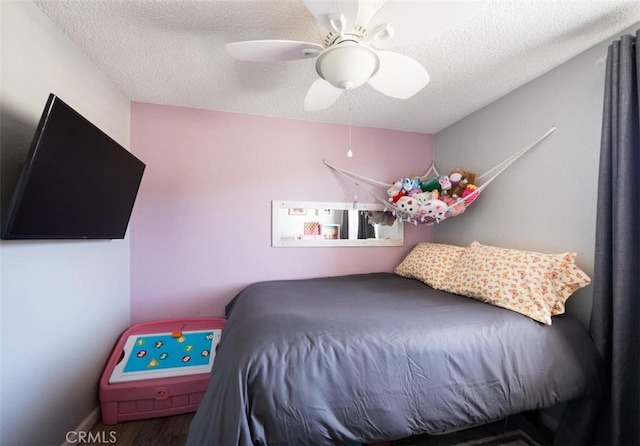 bedroom with baseboards, wood finished floors, ceiling fan, and a textured ceiling