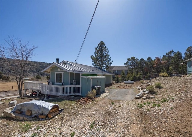 view of front of property featuring metal roof, a wooden deck, and fence