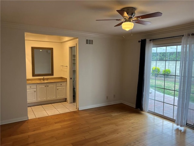 spare room featuring visible vents, light wood-style floors, baseboards, and a sink