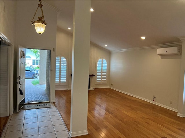 foyer entrance with plenty of natural light, a wall unit AC, crown molding, and wood-type flooring