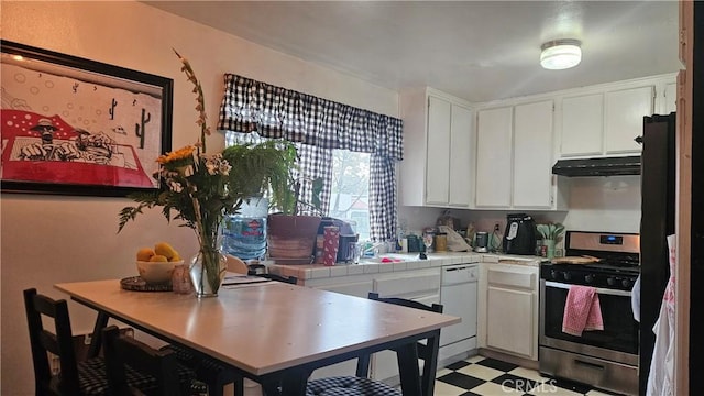 kitchen with stainless steel range with gas stovetop, under cabinet range hood, white dishwasher, tile countertops, and light floors