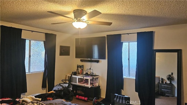 bedroom featuring a ceiling fan, a textured ceiling, multiple windows, and carpet flooring