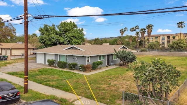 ranch-style home with fence, a detached garage, and a front lawn
