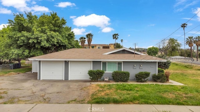 ranch-style home with fence, roof with shingles, a front yard, and an attached garage