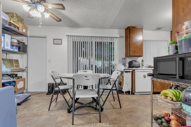 dining space with a textured ceiling, ceiling fan, and visible vents