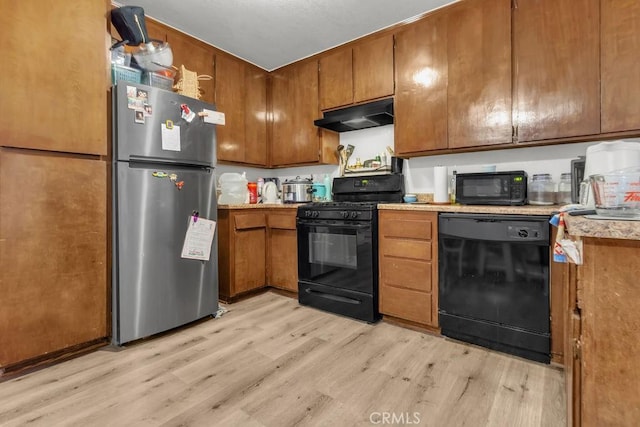 kitchen with light countertops, under cabinet range hood, black appliances, light wood-type flooring, and brown cabinetry