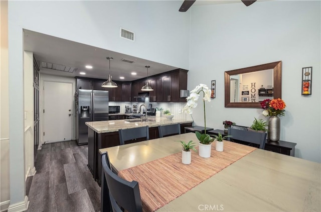 dining room featuring visible vents, a ceiling fan, dark wood finished floors, and a towering ceiling
