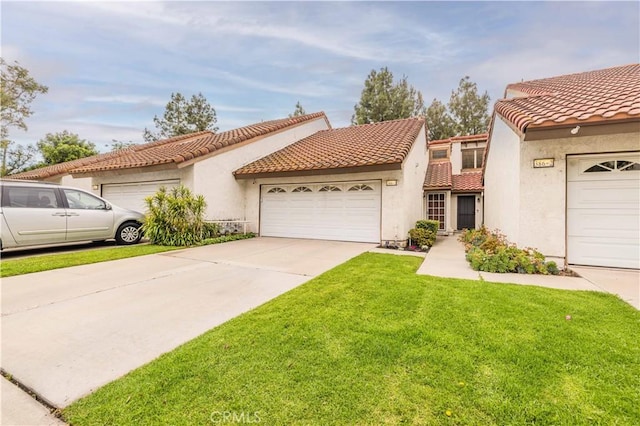 mediterranean / spanish-style home featuring an attached garage, stucco siding, a front yard, and a tile roof