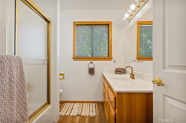 32991 Canyon Dr, Green Valley Lake, CA 92341 - bathroom featuring wood finished floors, enclosed tub / shower combo, toilet, vanity, and baseboards