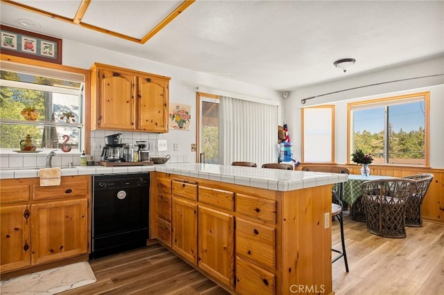 32991 Canyon Dr, Green Valley Lake, CA 92341 - kitchen featuring black dishwasher, tasteful backsplash, a peninsula, and light wood-style floors