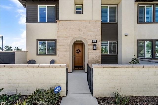 entrance to property with fence and stucco siding