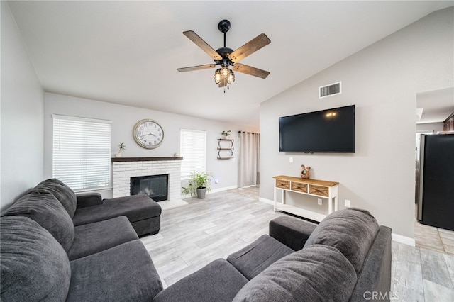 6932 Sundown Dr, Jurupa Valley, CA 92509 - living room with a fireplace, ceiling fan, visible vents, light wood-style flooring, and vaulted ceiling