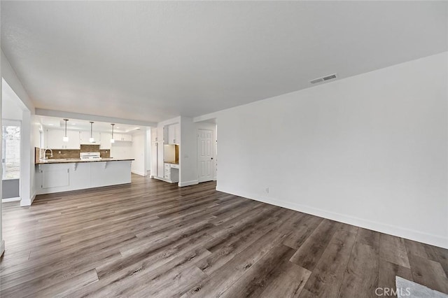 701 Black Oak Cir, Corona, CA 92881 - unfurnished living room featuring a sink, baseboards, dark wood-style floors, and visible vents
