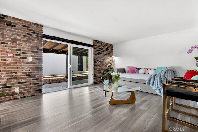 living area featuring brick wall and wood finished floors