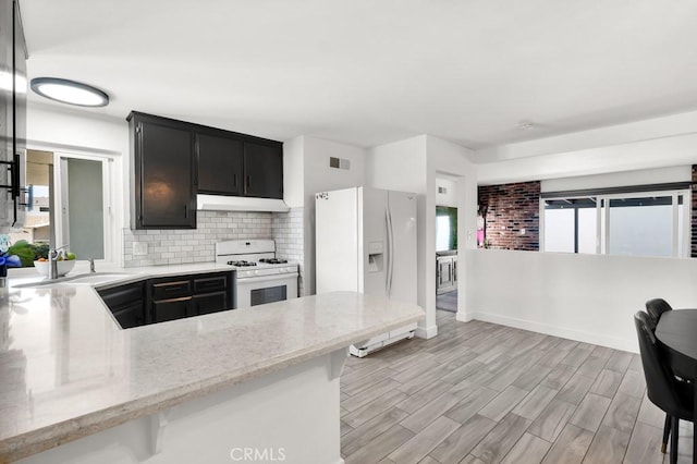 kitchen featuring dark cabinets, a sink, visible vents, white appliances, and under cabinet range hood
