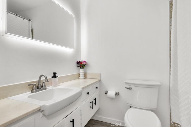 bathroom featuring vanity, toilet, and baseboards