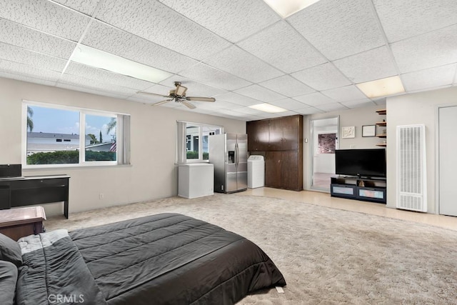 bedroom featuring a paneled ceiling, light colored carpet, stainless steel refrigerator with ice dispenser, and a heating unit